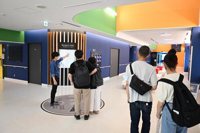 受付ホールにて治療の流れなどについて説明を受ける参加者